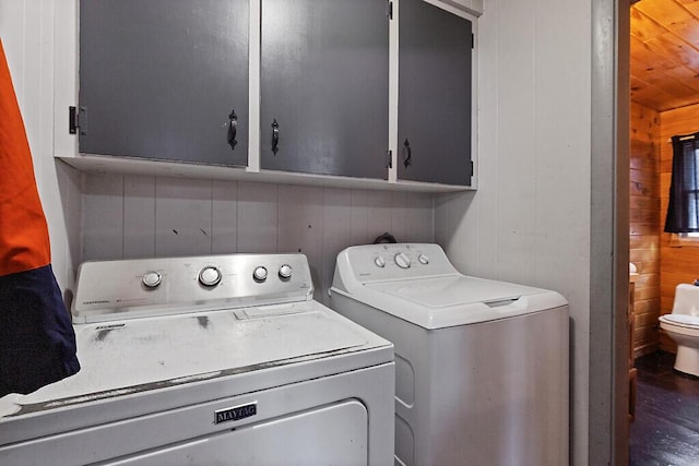 clothes washing area featuring wooden walls and washer and clothes dryer