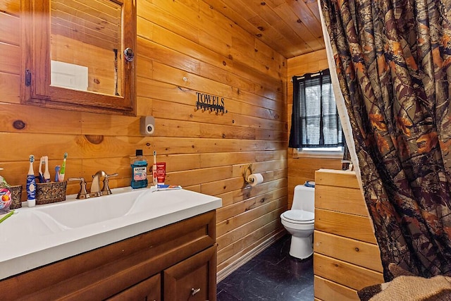 bathroom featuring wooden walls, vanity, and toilet