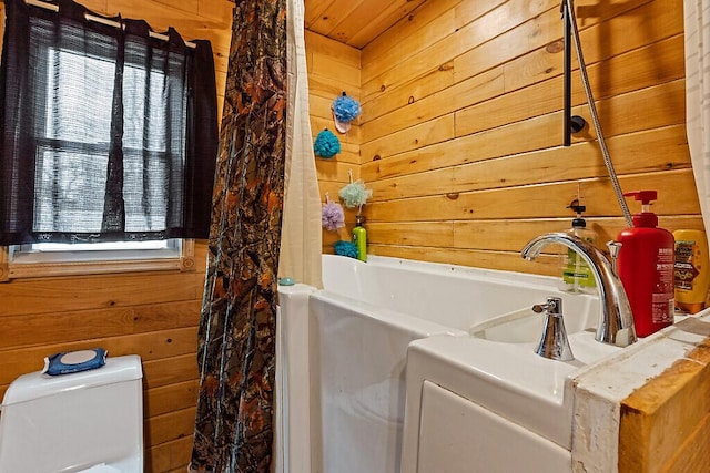 full bath featuring toilet, a washtub, a sink, curtained shower, and wooden walls