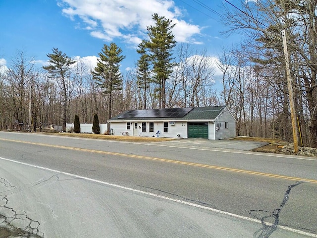 view of front of house with driveway, solar panels, an attached garage, and fence