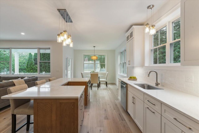 75 Main St, York, ME 03909 - kitchen featuring stainless steel dishwasher, light wood-style floors, light countertops, tasteful backsplash, and a breakfast bar