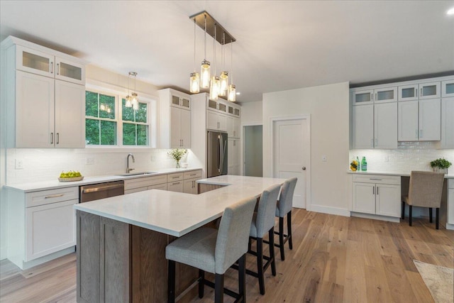 75 Main St, York, ME 03909 - kitchen featuring stainless steel appliances, backsplash, a kitchen bar, light countertops, and light wood-style flooring