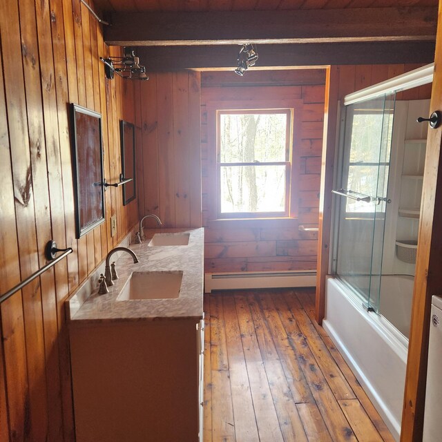 full bath with wooden walls, baseboard heating, and a sink