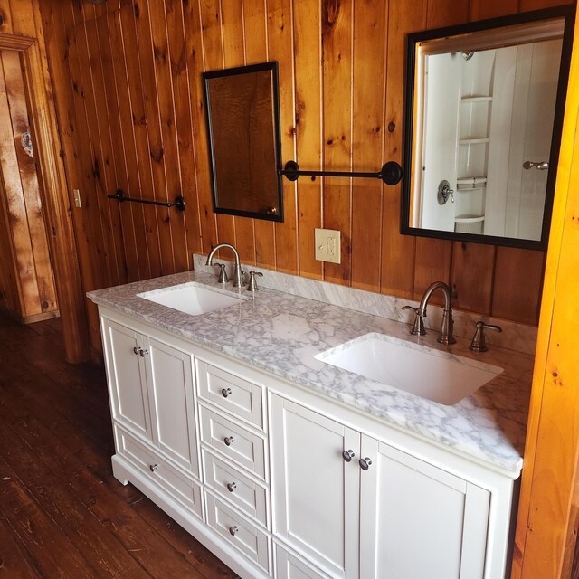 full bathroom with wood walls, wood finished floors, and a sink