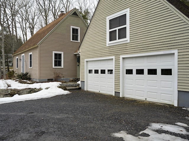 view of side of property with a garage, driveway, and a chimney