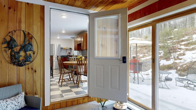 doorway with tile patterned floors, wooden walls, and wood ceiling