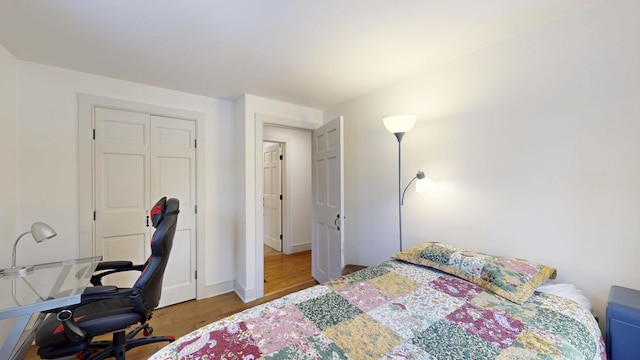 bedroom with a closet, baseboards, and wood finished floors