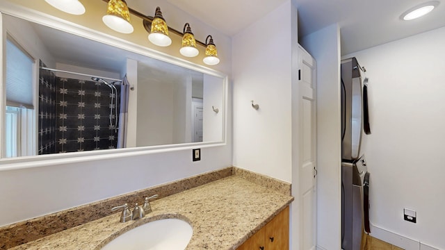 bathroom with vanity, stacked washer / dryer, and curtained shower