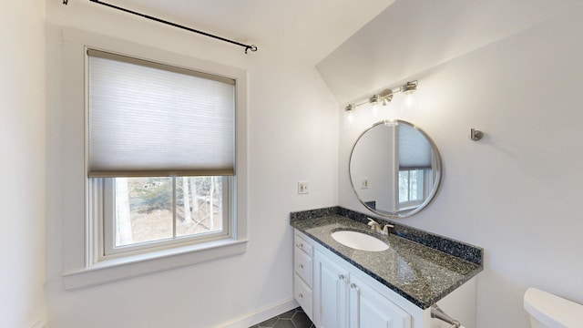 half bath with vanity, lofted ceiling, toilet, and baseboards