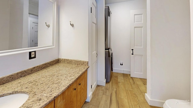 bathroom featuring baseboards, toilet, wood finished floors, and vanity