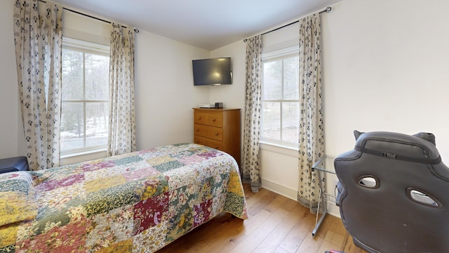 bedroom featuring hardwood / wood-style floors, multiple windows, and baseboards