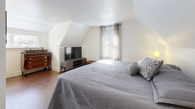 bedroom with baseboards, wood finished floors, and vaulted ceiling