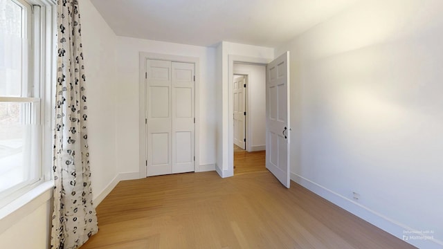 unfurnished bedroom with light wood-type flooring and baseboards