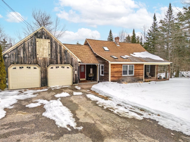 view of front of house with a shingled roof, aphalt driveway, a garage, and a chimney