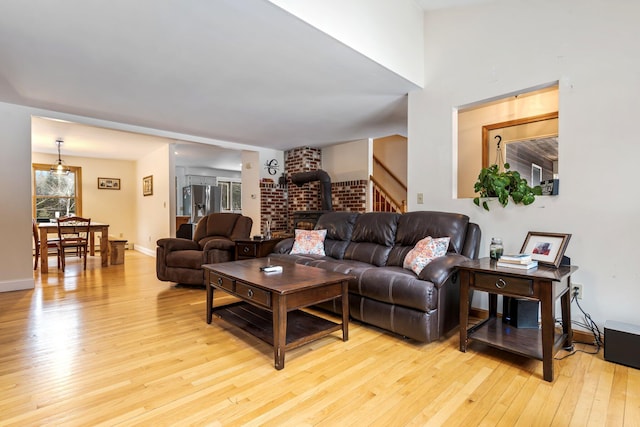 living area with baseboards, light wood-type flooring, and a wood stove