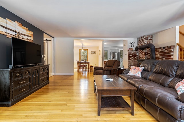 living area with a barn door, baseboards, light wood-style floors, and a wood stove