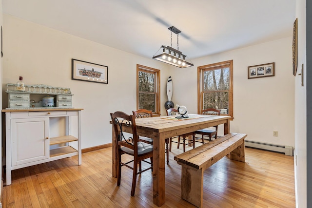 dining area with a baseboard heating unit, light wood-style floors, and baseboards