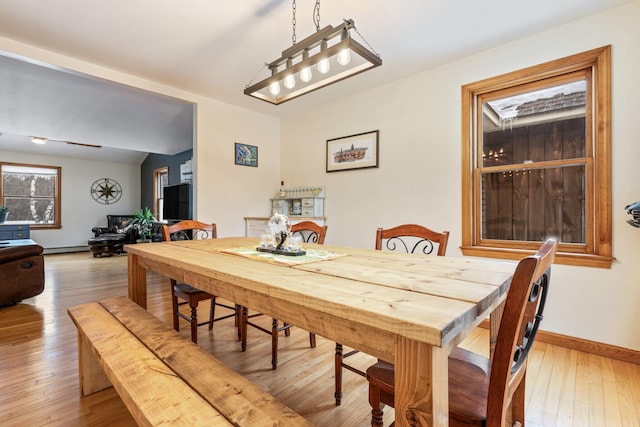 dining space featuring baseboards and light wood finished floors