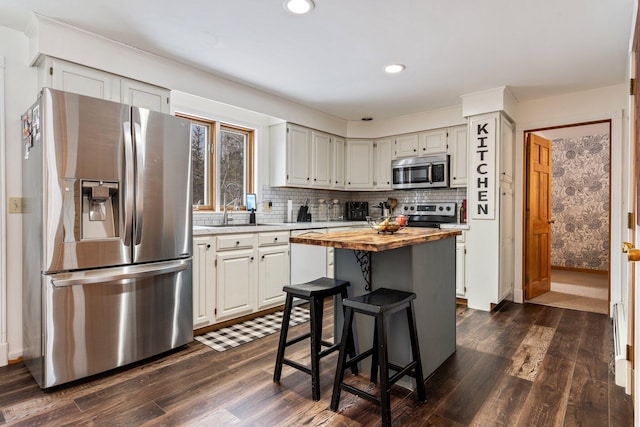 kitchen featuring a sink, stainless steel appliances, dark wood-style flooring, and butcher block counters