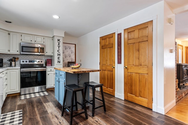 kitchen featuring stainless steel appliances, baseboards, tasteful backsplash, and dark wood finished floors