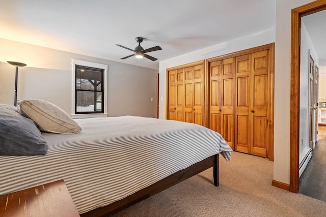 carpeted bedroom featuring baseboards, a ceiling fan, a baseboard heating unit, and multiple closets