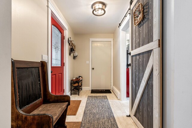 doorway featuring light tile patterned floors, baseboards, and a barn door