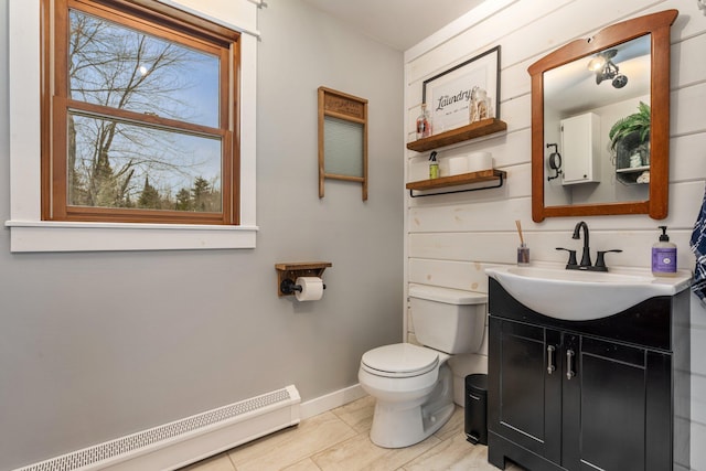 half bathroom featuring vanity, baseboards, tile patterned flooring, toilet, and baseboard heating