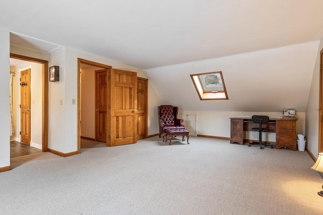 living area featuring baseboards, lofted ceiling with skylight, and carpet