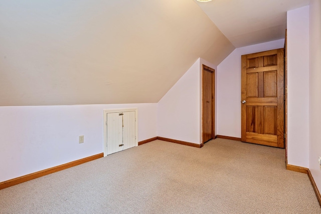 additional living space featuring vaulted ceiling, baseboards, and light carpet