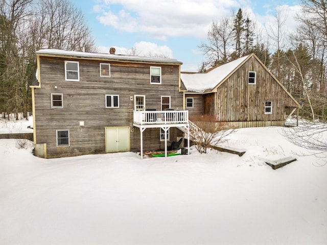 snow covered rear of property featuring a wooden deck and stairs