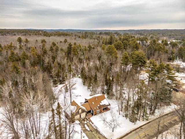 snowy aerial view featuring a wooded view