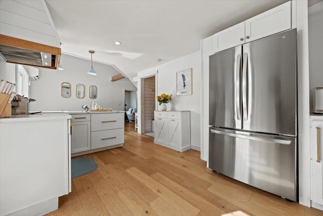 kitchen featuring light wood-type flooring, pendant lighting, freestanding refrigerator, light countertops, and vaulted ceiling