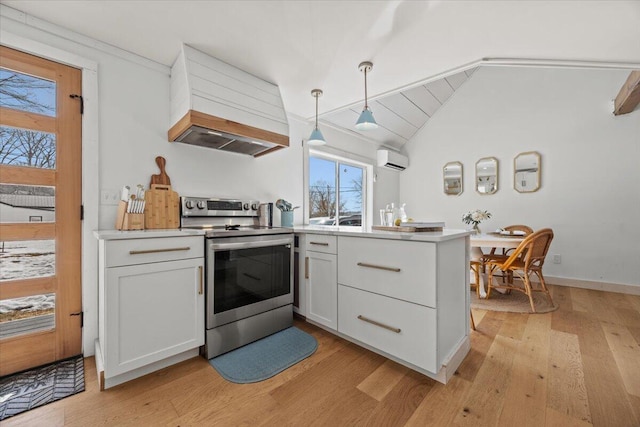 kitchen with premium range hood, an AC wall unit, stainless steel electric stove, light wood-style floors, and vaulted ceiling