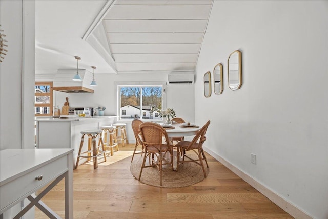 dining area with baseboards, a wall mounted AC, light wood-style floors, and vaulted ceiling