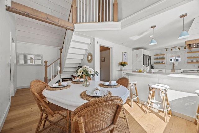 dining area featuring stairs, lofted ceiling, light wood-style flooring, and baseboards