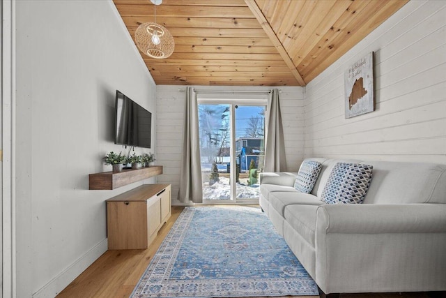 living area featuring wooden walls, baseboards, lofted ceiling, light wood-style flooring, and wood ceiling