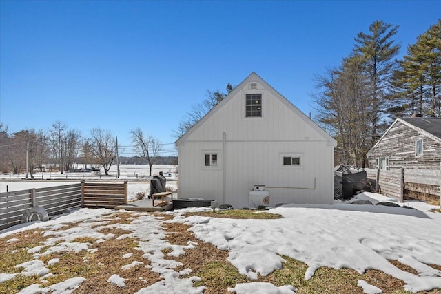 snow covered property with an outbuilding and fence