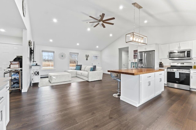 kitchen featuring dark wood-style floors, wooden counters, stainless steel appliances, a kitchen bar, and open floor plan