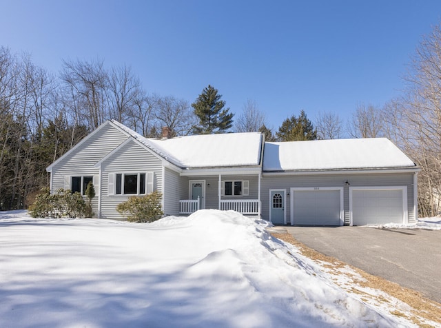 ranch-style home featuring aphalt driveway, covered porch, a chimney, and a garage