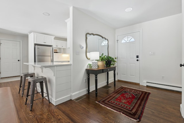 entryway featuring dark wood-style floors, visible vents, baseboards, and a baseboard radiator