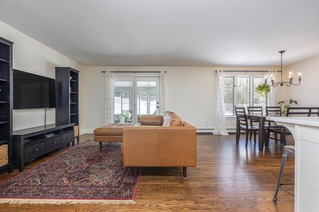 living area featuring dark wood finished floors, plenty of natural light, baseboards, and a notable chandelier