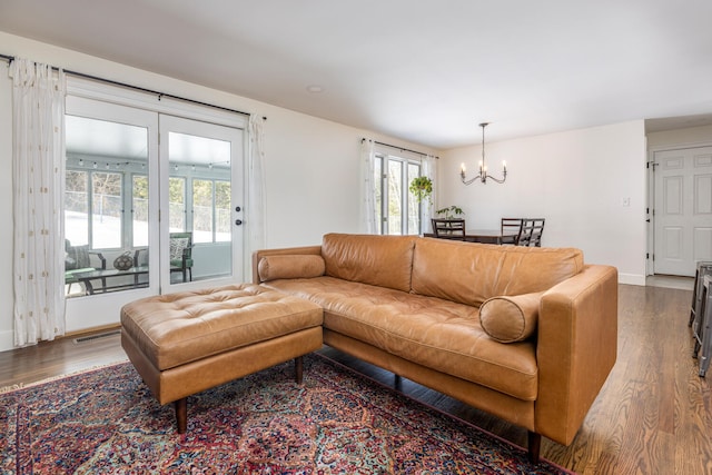 living area with visible vents, baseboards, a notable chandelier, and wood finished floors