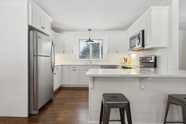 kitchen featuring a sink, appliances with stainless steel finishes, a peninsula, and white cabinets