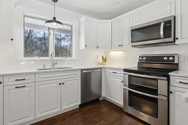 kitchen with dark wood finished floors, a sink, white cabinets, appliances with stainless steel finishes, and tasteful backsplash