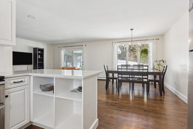 dining space with a notable chandelier, baseboards, dark wood-type flooring, and a healthy amount of sunlight