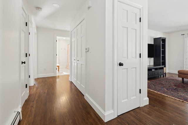 hallway with a baseboard radiator, baseboards, and wood finished floors