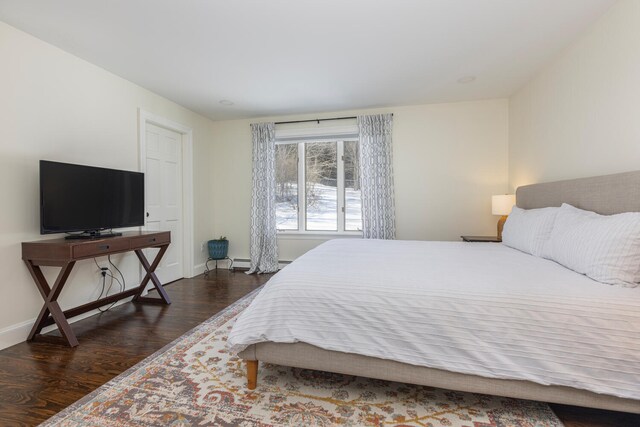 bedroom featuring a baseboard heating unit, baseboards, and dark wood-style flooring