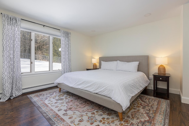 bedroom with baseboard heating, baseboards, and wood finished floors