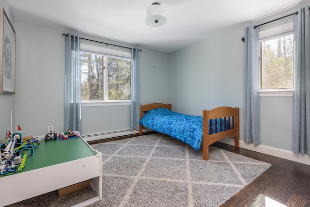 bedroom featuring baseboards, multiple windows, baseboard heating, and wood finished floors