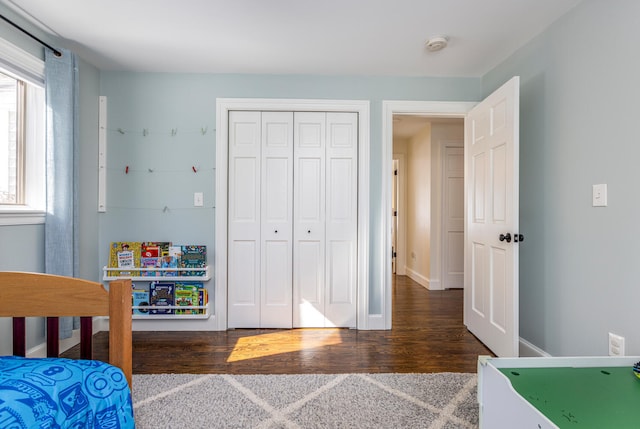 bedroom with wood finished floors, a closet, and baseboards